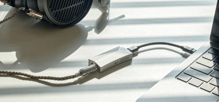 Sortøjse i sort, flettet kabel, sølvfarvet lydtilslutning, grå bærbar computer, oversigt fra oven