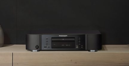 Leitor de CD hi-fi preto em metal, vista frontal, gaveta frontal, tela, botões, porta USB, saída para fones de ouvido e pés prateados