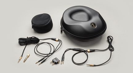 Topview af et sæt lydtilbehør bestående af et sort, hårdt etui i formstøbt plast med lynlås, en lille sort tekstilpose samt flere sorte lydkabler med guldbelagte stik og adaptere