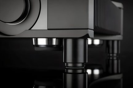 Czarny wzmacniacz hi-fi z metalu, zbliżenie na obudowę z okrągłym pokrętłem i cylindrycznymi nóżkami