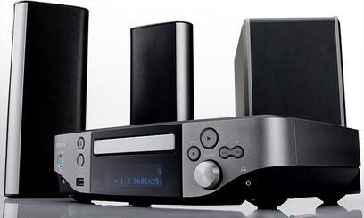 Denon S-302 hjemmebiografsystem bestående af to sorte højttalere, en sort subwoofer og en grå metallic forstærker, set forfra