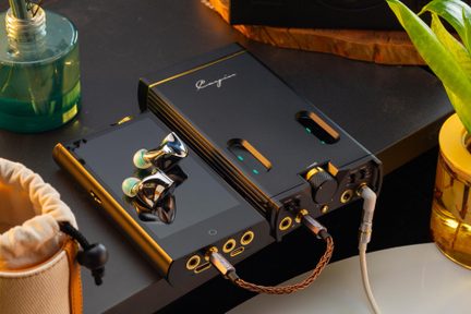Zwarte audiospeler, chroomkleurige in-ear oordopjes met turkoois dopjes erop geplaatst, verbonden met een zwarte versterker, bovenaanzicht