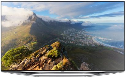 Samsung UE46H7000-fjernsyn, der viser et luftfoto af et klippefyldt bjerg omgivet af skyer og med udsigt over en kystby