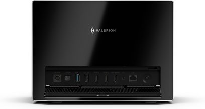 Projektor Valerion VisionMaster Max w kolorze błyszczącej czerni, wykonany z polerowanego plastiku, widok z tyłu ukazujący rząd portów: DC 36 V, S/PDIF, USB 3.0, USB 2.0, trzy HDMI, audio, LAN oraz przycisk zasilania umieszczony nad kratką wentylacyjną w prostokątnej obudowie z metalowymi krawędziami