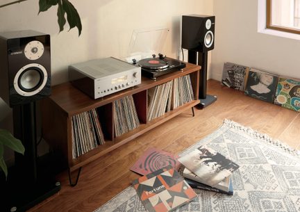 Hi-fi-anlæg på træmøbel, pladespiller med gennemsigtigt låg, sølvfarvet forstærker, vinyler opbevaret, sorte højttalere på standere