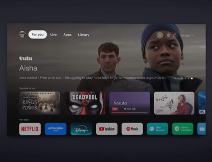 Vedere frontală a unui ecran plat negru din sticlă afișând interfața Google TV în modul întunecat, cu bară de file albă, banner mare de serial și pictograme multicolore ale aplicațiilor