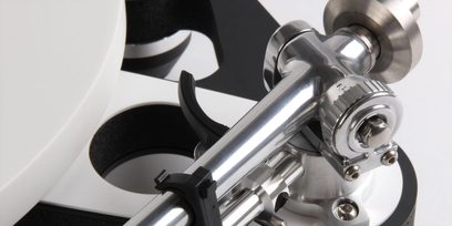 Rameno pro gramofon Rega RB3000, detailní záběr, stříbrný povrch, černý držák, bílé podložky na pozadí