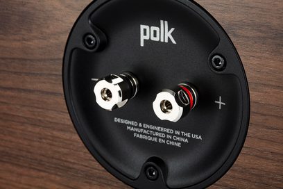 Černý centrální reproduktor Polk, detailní pohled zepředu, stříbrné ovládací tlačítka, nápis "polk +" na přední straně