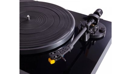 Sort vinylplade med blank overflade, stribet drejeskive med central akse, metal tonearm og gul pickup, tæt på-billede