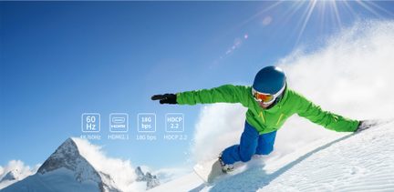 Snowboarder i grøn heldragt, der suser ned ad en snedækket bakke under blå himmel, 4K 60 Hz HDMI 2.1 18 Gbps visuals