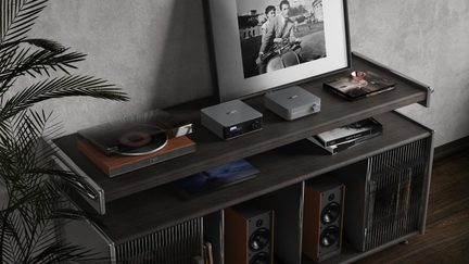 Player de rețea și amplificator WiiM gri pe mobilier hi-fi din lemn închis la culoare, cu pick-up și boxe