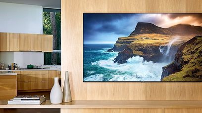 Samsung QE55Q70R-tv, der viser et billede af klippeformationer og brusende bølger ved havets bred