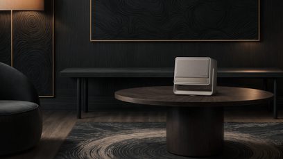 Videoproiettore XGIMI Horizon S Max su tavolo rotondo in legno, vista frontale, sfondo scuro con motivi circolari, lampada a sinistra