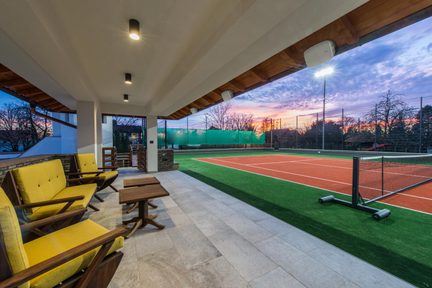 Diffusore da esterno bianco fissato al muro sotto una sporgenza del tetto su una terrazza coperta vicino a un campo da tennis