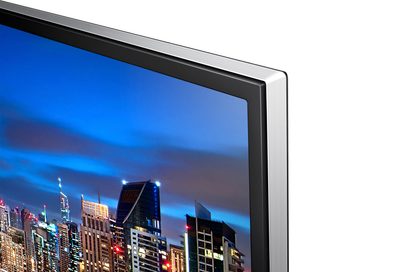 Samsung UE40HU6900 fladskærms-TV, smal sort ramme, set fra siden, viser en oplyst by om natten