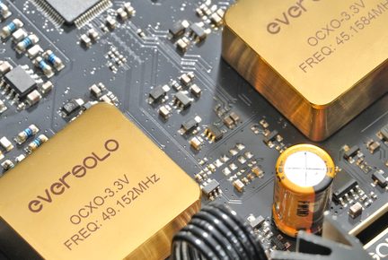 Nahaufnahme von elektronischen Komponenten auf einer Hauptplatine, vergoldete Gehäuse, orangefarbener zylindrischer Kondensator, Leiterplatten