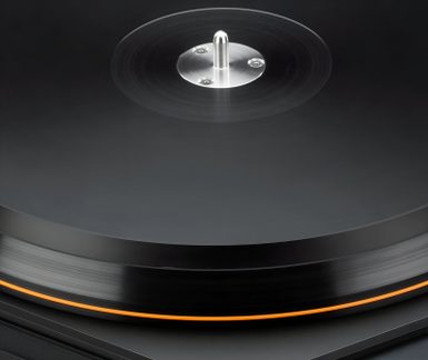 Platine vinyle noire vue de près, plateau en rotation avec bord lumineux orange et axe central en métal