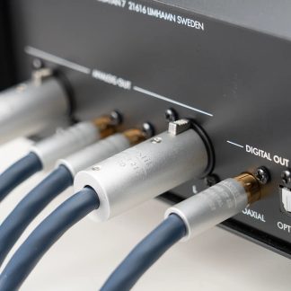 Tæt billede i sidevisning af den sorte bagside af et lydapparat, der viser flere cylindriske metalforbindelser i sølvfarvet metal og tykke kabler med mørkeblå kapper