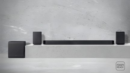 Černý soundbar se subwooferem a dvěma zadními reproduktory, pohled zepředu na světle šedém pozadí