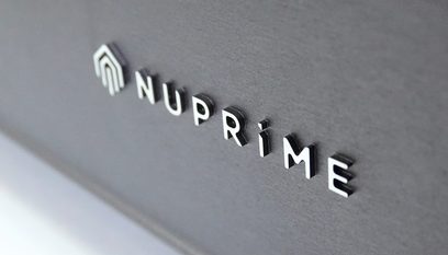 Vysokofidelitní výkonový zesilovač Nuprime AMG STA Silver, detailní pohled zepředu na reliéfní logo na předním panelu