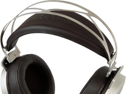 Suure lähedusega külgvaade STAX SR-007S avatud traadiga hifi-kuulokite ajuriga ja vasakust küljest, hõbedaseks harjatud alumiiniumraamiga, ümberkuulokitega ja pruuni nahkse peahoovõruga, nähtava metallvõrega tagumisel küljel