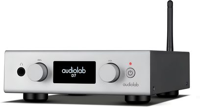 Slúchadlový predzosilňovač Audiolab D7 striebornej farby z brúseného hliníka, pohľad z troch štvrtín spredu, predný panel s dvoma kruhovými tlačidlami, čierny centrálny displej zobrazujúci názov, slúchadlový výstup, tlačidlo napájania s červenou LED a čierna zadná anténa
