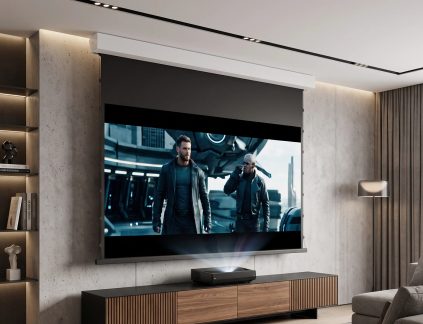 Nástěnné projekční plátno s černým rámem a bílým krytem, na němž se promítá film nad projektorem s krátkou projekční vzdáleností