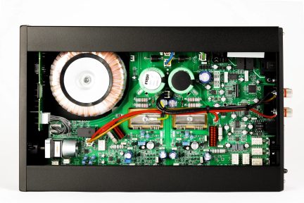 Top view of an open electronic case with green printed circuit boards, cylindrical components, colored wires, and connectors