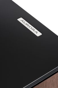 Grindinė kolonėlė AURORA XT 700, stambiu planu matomas juodas matinis viršus su stačiakampiu sidabriniu įdėklu, ant kurio užrašyta "AURORA".