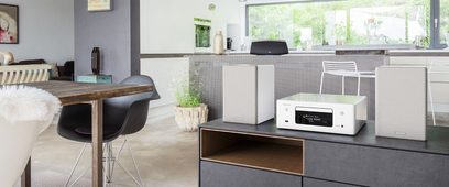 Denon RCD-N10 hvidt "alt-i-ét" hi-fi-system i et moderne interiør med grå møbler og grønne planter