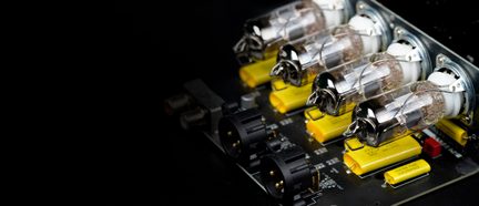 Nærbillede af elektronisk printkort til rørforstærker med fire rør, gule kondensatorer og sorte stik