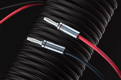 To sorte, flettede Triangle SYS50A-lydkabler (2 x 5 m) med røde metalstik, på sort baggrund