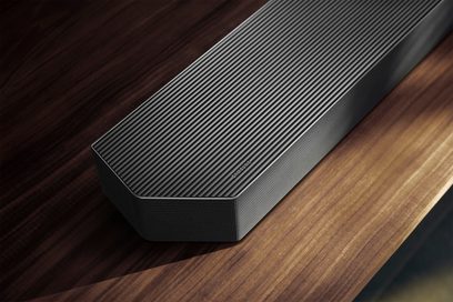 Schwarze Samsung-Soundbar aus Metall, aus schräger Vogelperspektive aufgenommen, Oberseite mit feinen parallelen Rillen versehen, Front- und Seitenflächen mit mikroperforiertem Gitter abgedeckt