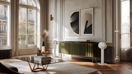 Salone, finestre ad arco, parquet in legno, credenza metallica verde, due casse acustiche sferiche bianche su piedistalli, tavolino basso in vetro