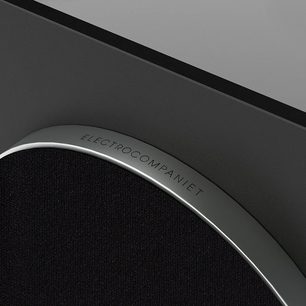Cassa dei bassi Sira L-1, vista parziale angolare, bordo argentato curvato con iscrizione, superficie nera testurizzata, sfondo grigio