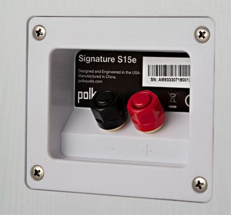 Polk Audio S15e baltų knygų lentynų garsiakalbis, priekinis vaizdas, su dviem raudonais ir juodais garsiakalbiais ant baltos plokštės