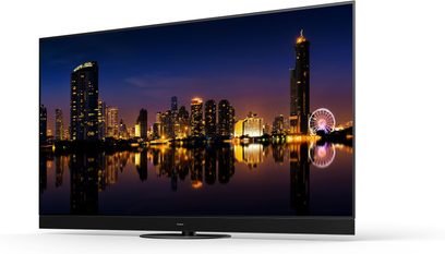 Téléviseur Panasonic TX-65MZ1500E allumé, vue de face, affichant une ville illuminée et sa réflexion sur un plan d'eau la nuit