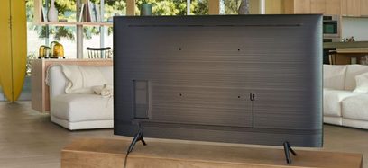 Samsung QE55Q70R fladskærms-TV, rektangulær sort skærm på metalben, i en moderne og lys stue