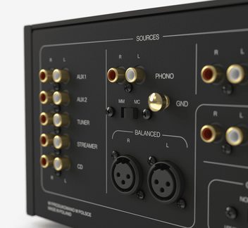 Černý kovový zadní panel audio zařízení, pozlacené RCA konektory, XLR R/L, přepínač phono MM/MC a svorka GND, šikmý pohled
