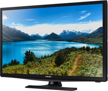 Samsung UE28J4100 tv der viser et blåt bjerglandskab med sø omgivet af vegetation, set forfra