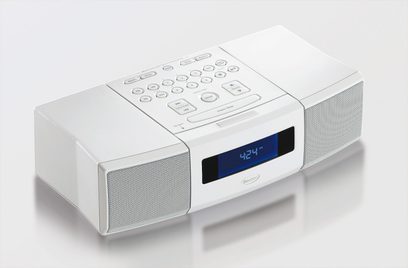 Radio-réveil blanc Boston Acoustics avec écran LCD bleu, boutons et molettes sur le dessus, deux haut-parleurs sur les côtés