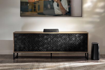 Træ-TV-møbel med sort Polk Audio MagniFi Mini AX soundbar med geometriske mønstre, under en vægmonteret TV