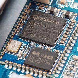 Qualcomm QCC3008-processor på blåt printplade med forgyldte og forsølvede elektroniske komponenter