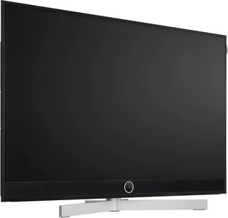 Плоскоекранний телевізор Loewe Stellar 42 DR+ чорного кольору, вигляд спереду під легким кутом, з інтегрованим саундбаром і сріблястою підставкою