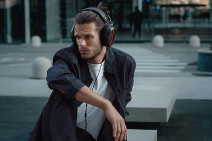 Schwarzer und kupferfarbener Hi-Fi Over-Ear-Kopfhörer, getragen von einem Mann in Jeansjacke, moderne urbane Atmosphäre