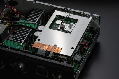 Interiørvisning av en svart Denon PMA-900HNE hi-fi forsterker som viser de elektroniske komponentene på et metallchassis