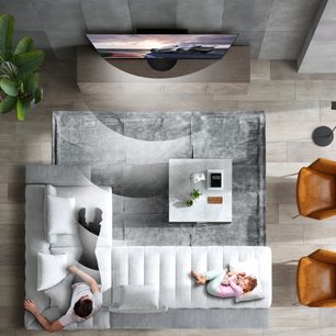 Moderne stue set ovenfra med gråt sofa, tæppe, hvidt sofabord, grønne planter og fladskærms-tv indbygget i en trævæg