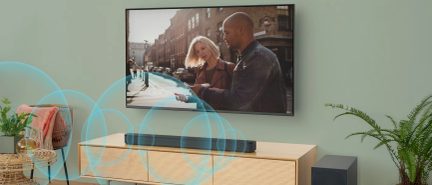 Fladskærms-tv på væggen, gadebillede, lys træmøbel, sort soundbar, grøn plante, rattan sofabord