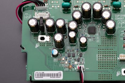 Placa de circuito impresso verde com condensadores eletrolíticos e componentes eletrônicos do leitor de CD Marantz CD6007 prateado dourado, vista aproximada