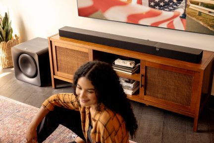 Soundbar Teufel nera con subwoofer abbinato, posizionata su un mobile TV sotto un televisore